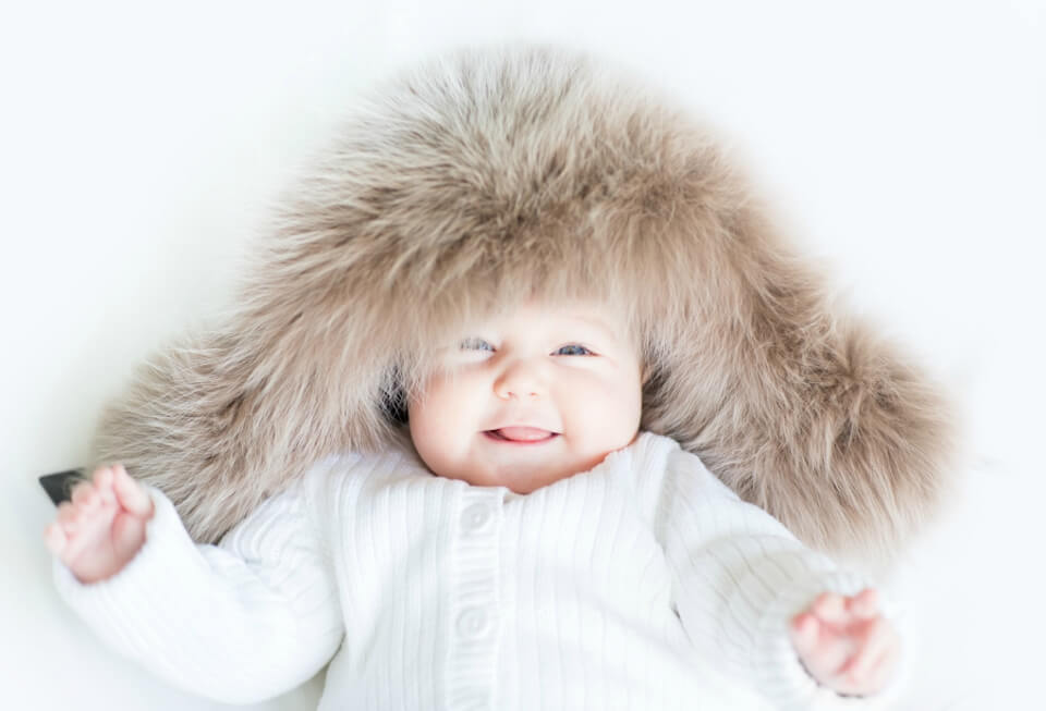 Laughing baby in a big fur hat